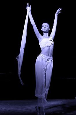 Una ballerina di danza classica esegue un'elegante performance in un'atmosfera suggestiva, vestita di bianco, con un drappo in movimento. Scattata a Viterbo.