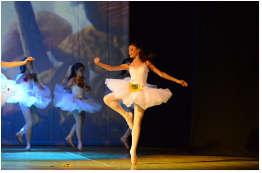 Ballerina Classica in Retiré - Spettacolo Alice nel Paese delle Meraviglie Ballerina classica in primo piano esegue un elegante retiré sulla punta durante lo spettacolo "Alice nel Paese delle Meraviglie" del Centro di Produzione Danza e Recitazione Viterbo